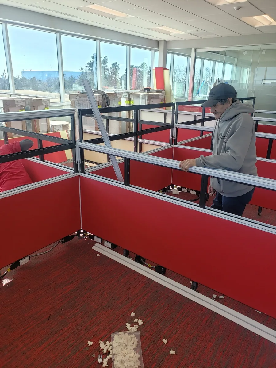 Bird Dog crew member assembling a red-panel office workstation