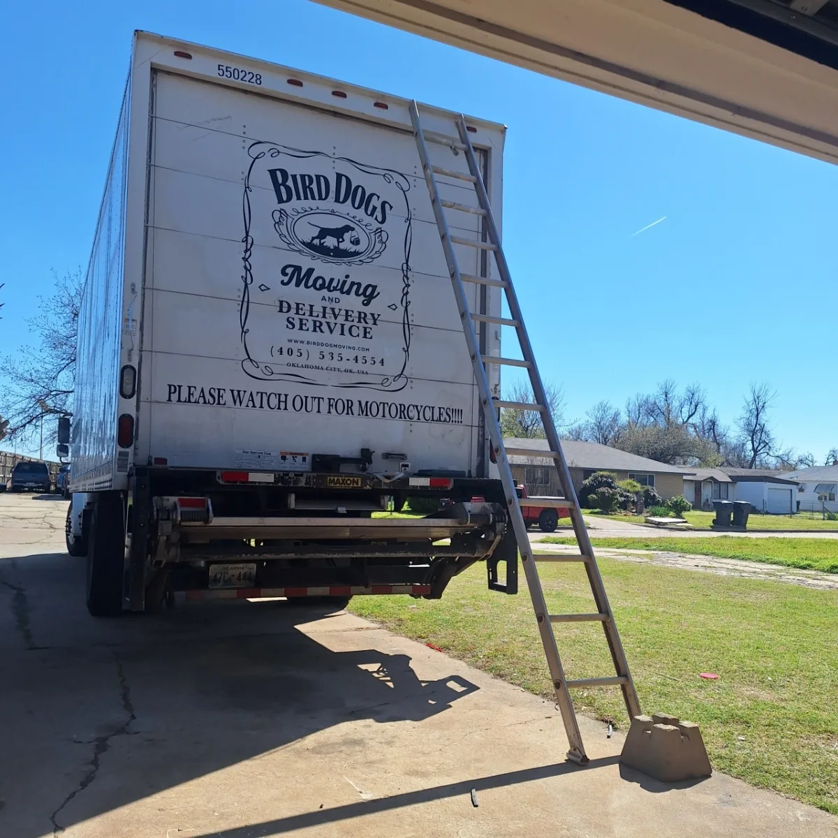 Bird Dog box truck backed up to a house with the loading ramp down